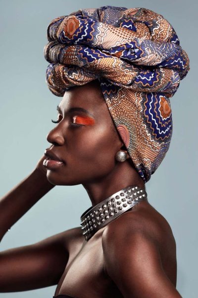 tanzanian woman with snake print turban over hear working in fabrics shop .